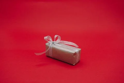 Small gray gift box with gray ribbon. Christmas gift box. Isolated on a red Stock Photos