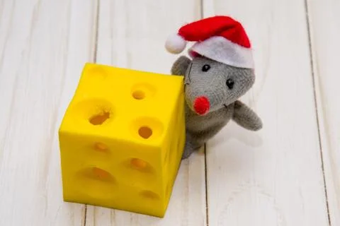 A small gray mouse with a piece of cheese on a wooden background. Stockfoto's