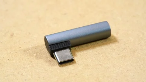 Small gray right-angle USB-C DAC audio adapter with exposed male connector .. Stock Footage 339372835
