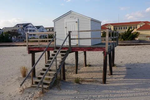 A small gray shack a platform raised above the sand on a beach Stock Photos