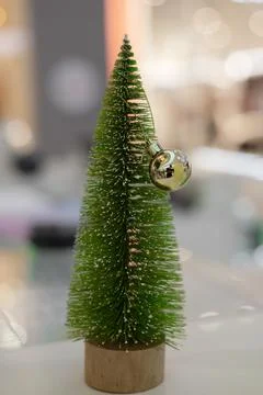 A small green artificial Christmas tree with white tips and a golden ball on a Stock Photos