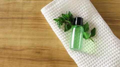 Small green bottle placed on a textured white cloth with fresh mint leaves on a Stock Photos