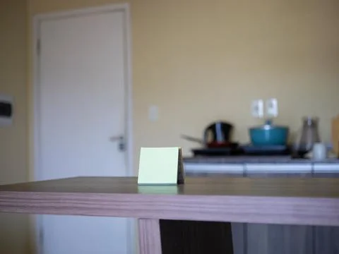 Small green sticky note on kitchen table Stock Photos