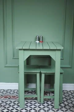 Small green table with stools in a simple room design Stock Photos