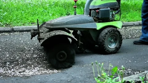 Small green vehicle with rotating brush used by worker to clean roadside, Stock Footage 330163377