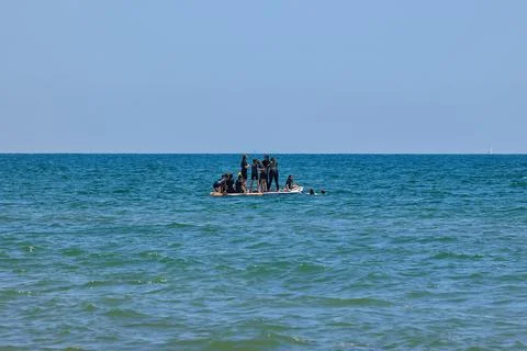 A small group of children having fun on one large Stand Up Paddle in the sea. Stock Photos