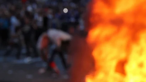 Small group of men pulling heavy rug and throwing it into fire during riot Stock Footage 127203001