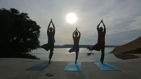 Small group of people doing yoga at sunrise on the background of the sea Stock Footage 102562295