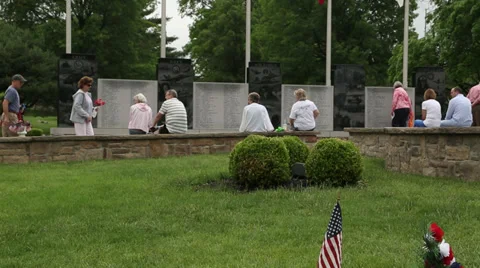 Small group of people walking and sitting by a war Memorial Stock Footage 38832038