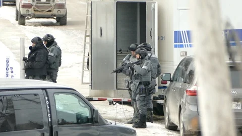 Small group of tactical cops walking in yard with snow towards house Stock Footage 88691068