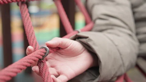 Small hand interacts with woven safety fence outside. Young child carefully Stock Footage 337371054