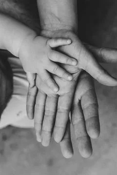 Small hand rests gently on larger hands Stockfoto's