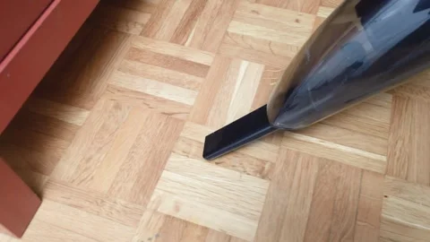 Small hand vacuum cleaner sweeping a wooden parquet room floor Stock Footage 263428883