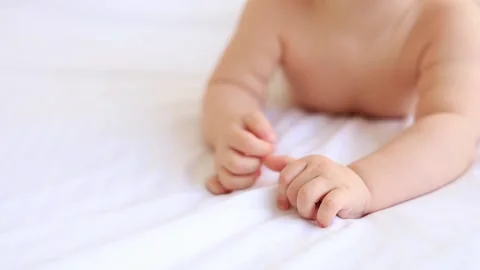 Small hands and fingers of a newborn baby on a white cotton bed at home Stock Footage