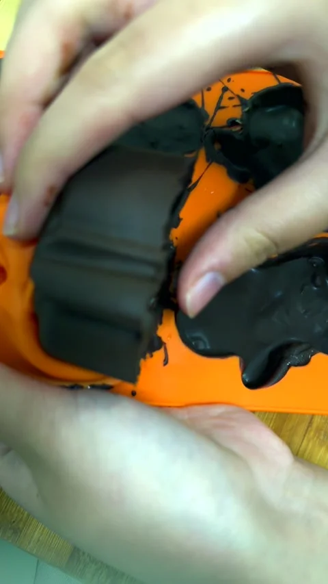 Small hands carefully press chocolate pumpkin out of silicone mold. Finished Video stock 343478262