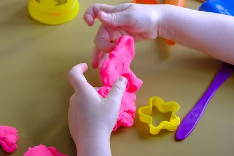 Small hands shape pink play dough with gentle care Stock Photos