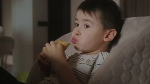 Small handsome boy sitting at the table on high-chair eating freshly baked pies Stock Footage 237587435