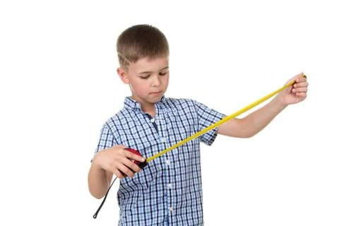 A small handsome builder boy in blue checkered shirt looks at a measuring tape Stock Photos