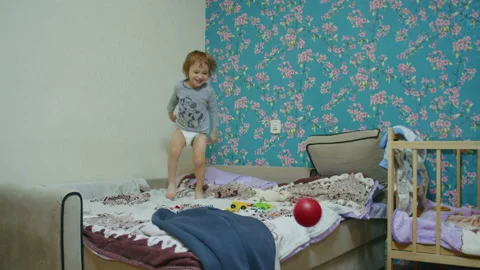 A small happy child jumps on the bed at home and plays ball with his father, the Stock Footage 170388546