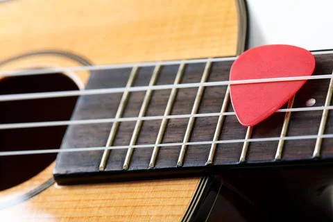Small Hawaiian four stringed ukulele guitar with red pick between strings c.. 스톡 사진