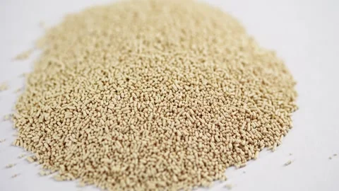 A small heap of dry active yeast granules centered on a clean white surface. Video stock 333571042