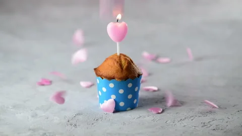 Small hearts are falling on a festive cupcake with pink heart shape candle Stock Footage 146482248
