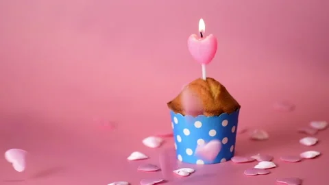 Small hearts are falling on a festive cupcake on pink background Stock Footage 146487790