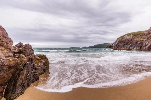 Small hidden beach between rocks and islands in the distance Stock Photos