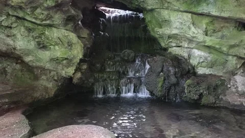 Small hidden waterfall inside a rock cave in Pierre Schneiter garden Reims Stock Footage 338387515