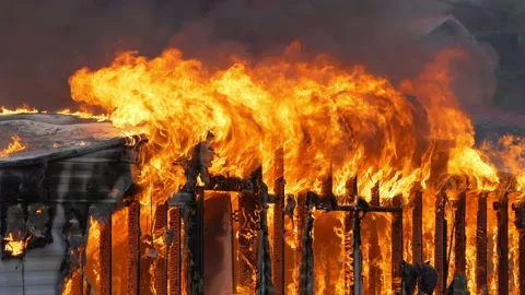 Small home engulfed in flames with a large fire. Slow motion footage of large Stock Footage 229816831