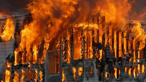 Small home engulfed in flames with a large fire. Slow motion footage of large Stock Footage 229816841