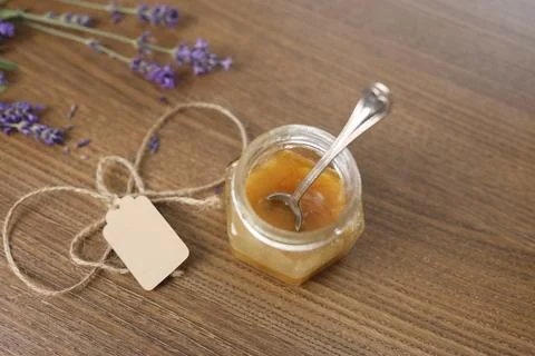Small honey glass jar string twine tag spoon inside wooden table top view. Fresh Stock Photos
