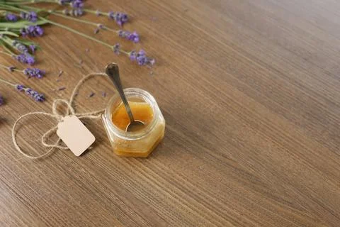 Small honey glass jar string twine tag spoon inside wooden table top view. Fresh Stock Photos