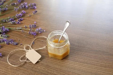 Small honey glass jar string twine tag spoon inside wooden table top view. Fresh Stock Photos