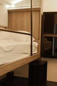 This small hostel room features a bunk bed, a television, and limited storage Stock Photos