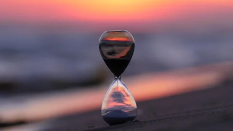Small hourglass on the beach during sunset, blurred background Stock Footage 314251475
