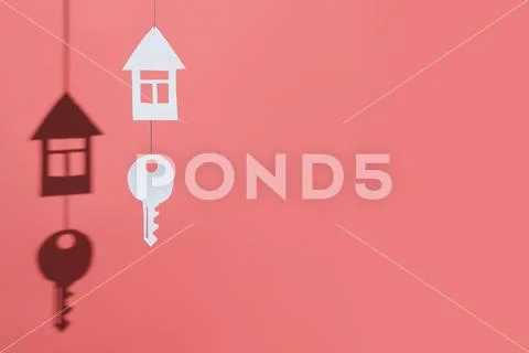 Small house and key made of cardboard casts a shadow on a bright colored back Stock Photos