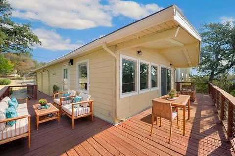 A small house features a large deck with a table and chairs Stock Photos