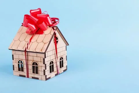 Small house model with red bow and ribbon on blue background Stock Photos