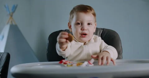 A small, hungry child eats and is fed by his mother at home. Medium shot. Stock Footage 150873736