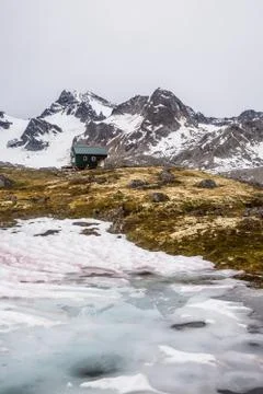 Small hut on a hill below massive glaciated peak in remote Alaska. Foto stock