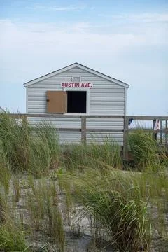 Small hut on a sandy beach surrounded by tall grass with it's window opened w Stock Photos