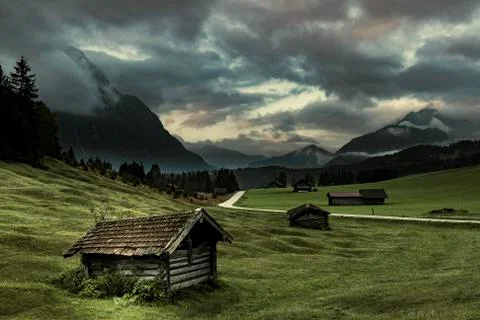 Small huts on mountain meadow with dramatic cloud sky and Wetterstein mountains Stock Photos