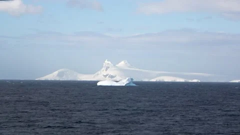 Small iceberg drifting mountain background Antarctica, 4K Stock Footage 332372809