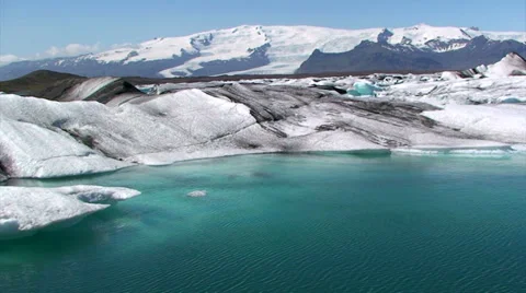 Small iceberg flows among larger icebergs, pan left following it Stock Footage 37898527