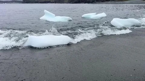 Small icebergs or glacial ice pieces washing ashore on a sandy beach by the sea. 스톡 동영상 343008601