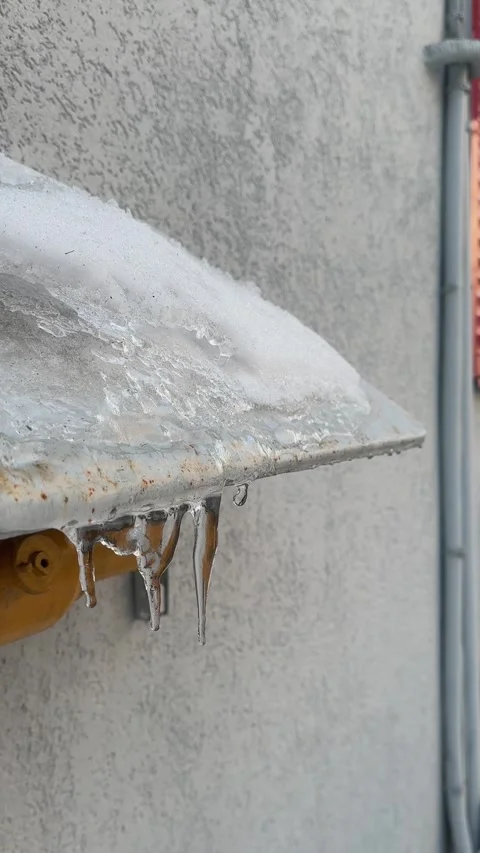 Small icicles thawing, dripping with water drops. Ice hanging from metal eaves Stock-Footage 304657262