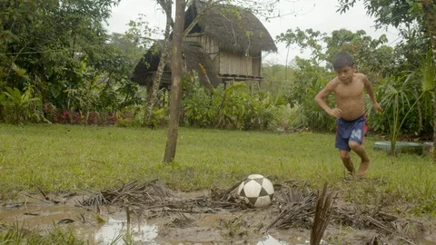 Small indigenous boy is kicking a ball out of a goal gate and gets dirty when Stock Footage 113179998