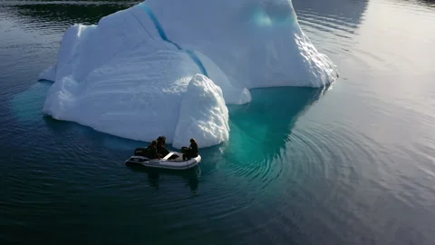 Small Inflatable Boat Beside Submerged Iceberg Shelf - Greenland Stock Footage 346572946