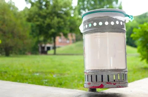 Small iron garbage can in public park with white plastic sign editable text Stock Photos